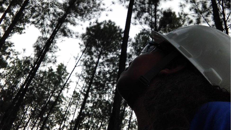 Paloma, wearing her hard hat and goggles, in the forest