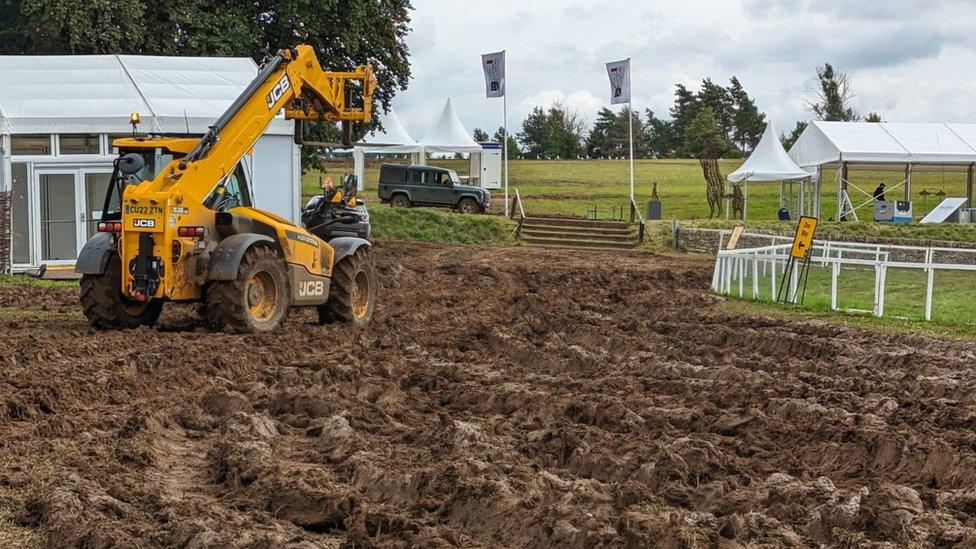 A yellow JCB in front of a white marquee