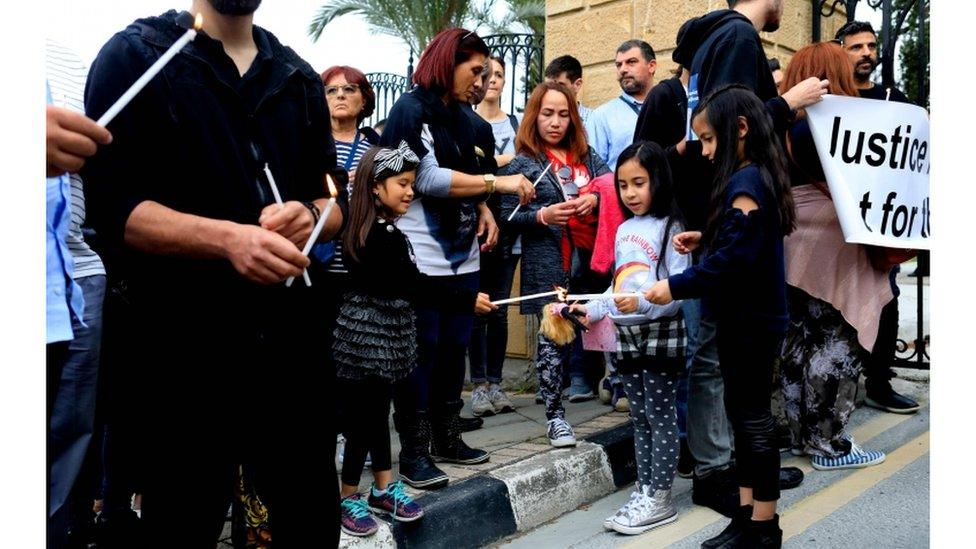 Migrant workers and their children lit candles to remember the victims of the murders at the vigil on April 26