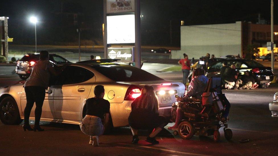 Protesters hide behind cars as shots heard in Ferguson, Missouri, on 9 August 2016