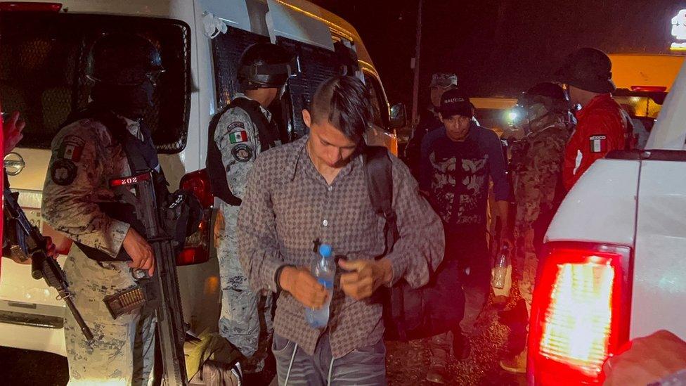 A group of migrants board a bus.