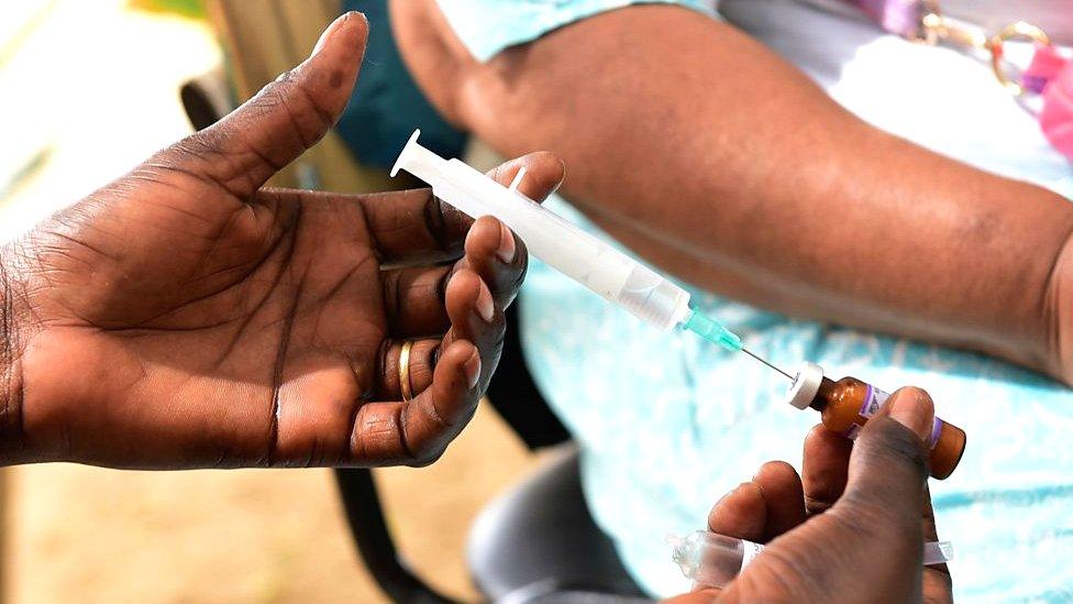 A nurse prepares a syringe before administering a vaccination against measles