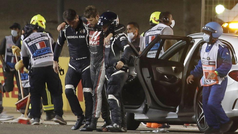 Grosjean (centre) was helped from the wreckage by a team of medics. He was protected from the flames by his specially made fire-proof suit