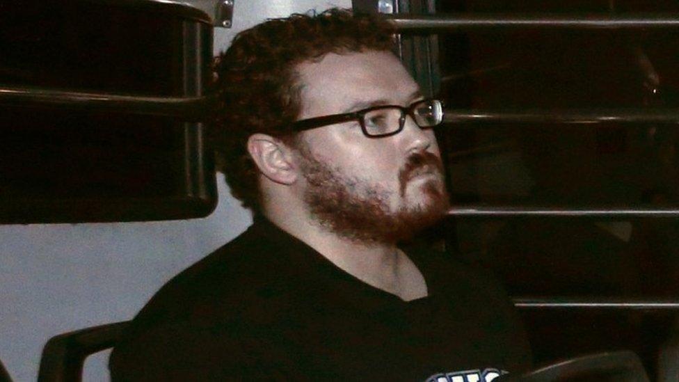 Rurik George Caton Jutting, a British banker charged with two counts of murder after police found the bodies of two women in his apartment, sits in the back row of a prison bus as he arrives at the Eastern Law Courts in Hong Kong November 24, 2014