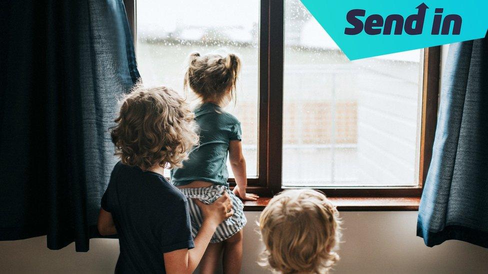 Children looking out of a rainy window.