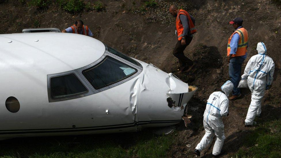 Forensic technicians and police officers from the Honduran National Police inspect the wreckage of a Gulfstream G200 aircraft