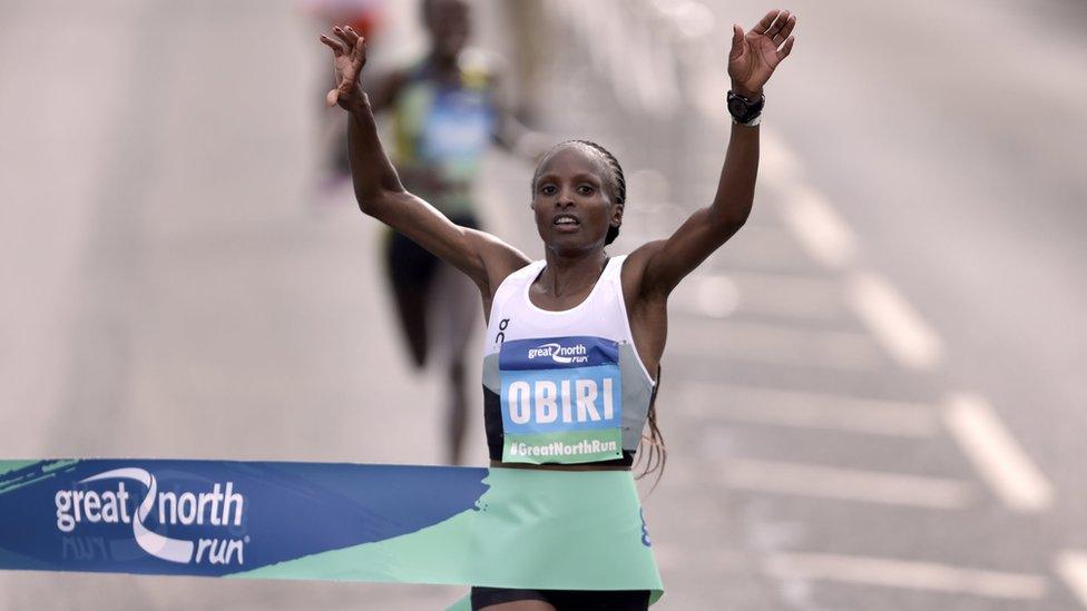 Hellen Obiri raises her arms as she crosses the finishing line