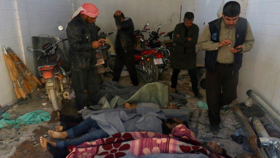 Men stand near dead bodies, after what rescue workers described as a suspected gas attack in the town of Khan Sheikhoun in rebel-held Idlib