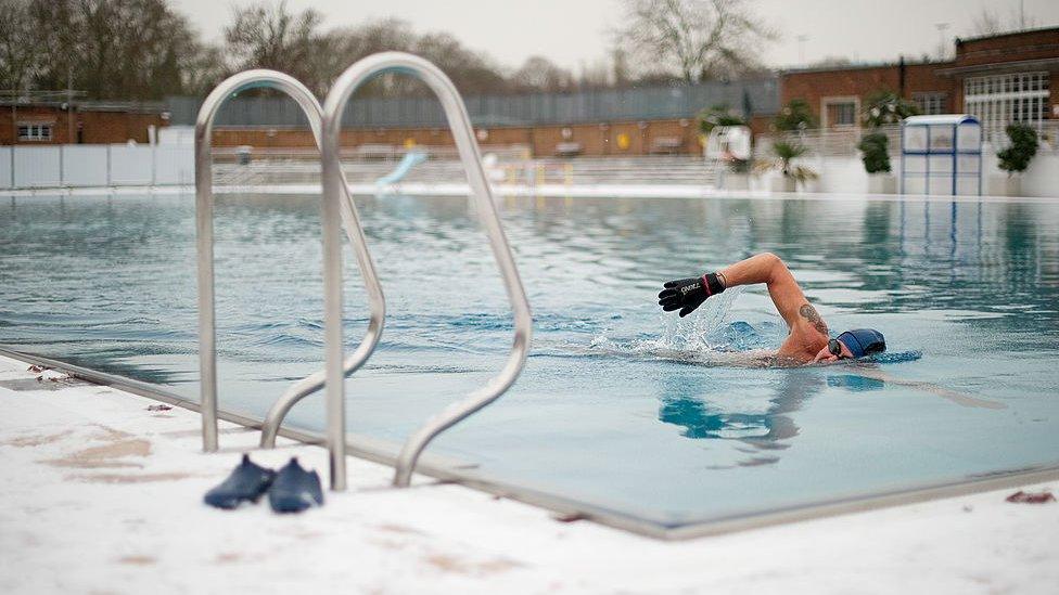 Man swims in the lido in snowy weather