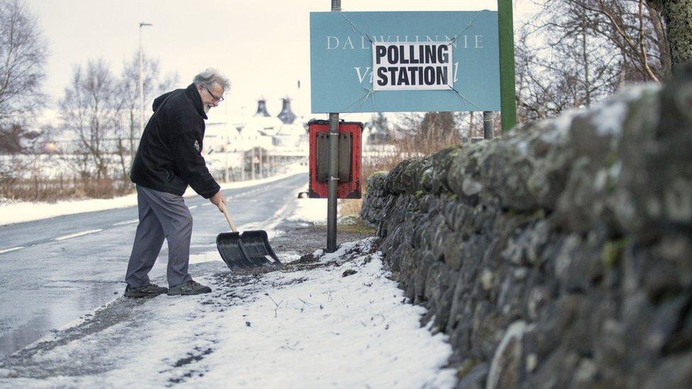 Man clearing snow outside a polling station