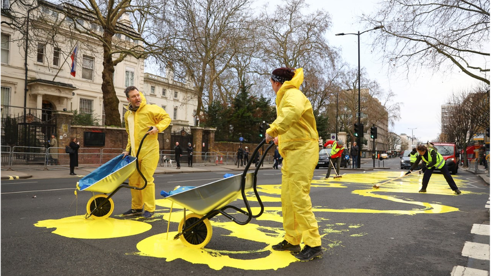 Two protestors pour yellow paint on the road