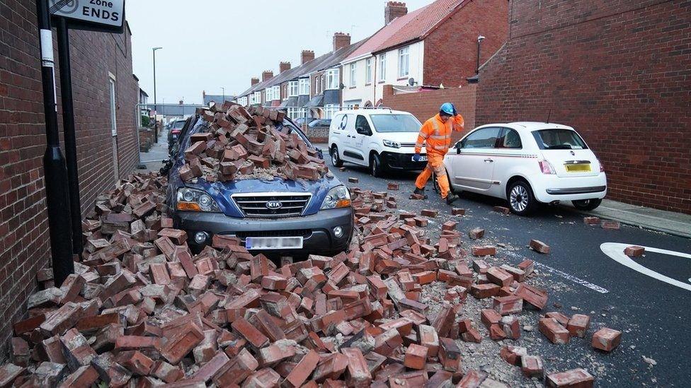 A man makes safe fallen masonry from a property, which has damaged a nearby car, on Gloucester Avenue in Roker, Sunderland