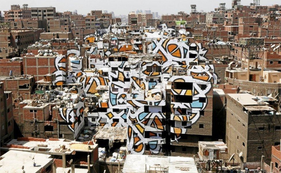 A mural painted on the walls of houses in Zaraeeb, created by French-Tunisian artist El Seed, is pictured in the shanty area known also as Zabaleen or "Garbage City" on the Mokattam Hills in eastern Cairo, Egypt, (photo release: 14 April 2016)