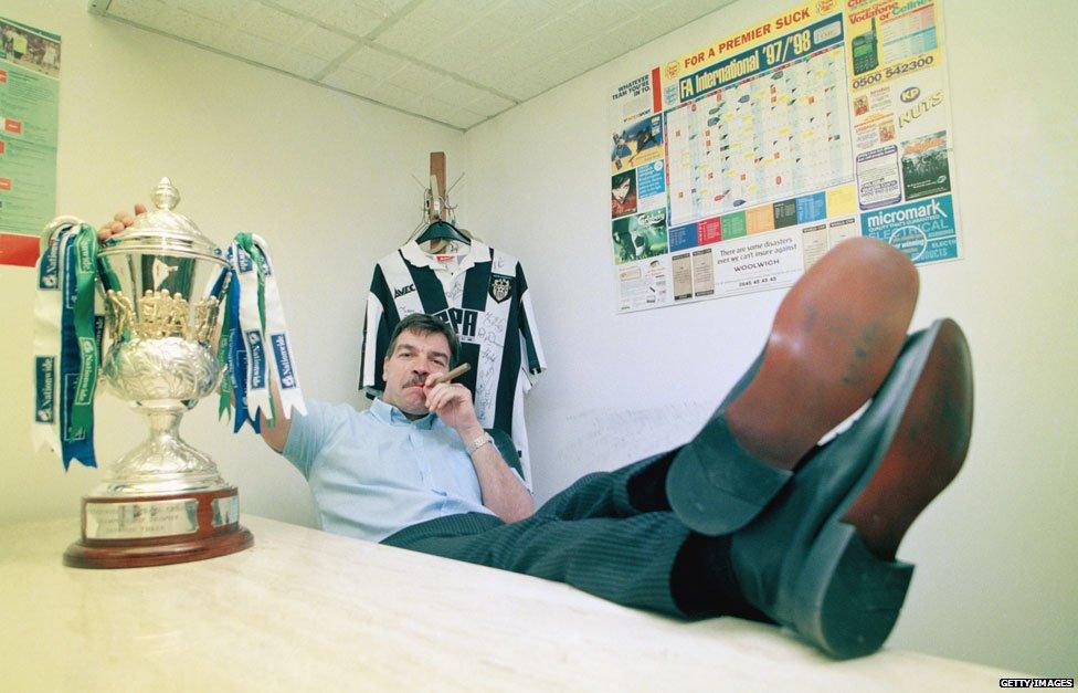 Sam smoking a cigar next to the trophy for winning Division Three