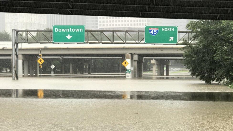 Flooded street below a sign to "Downtown"