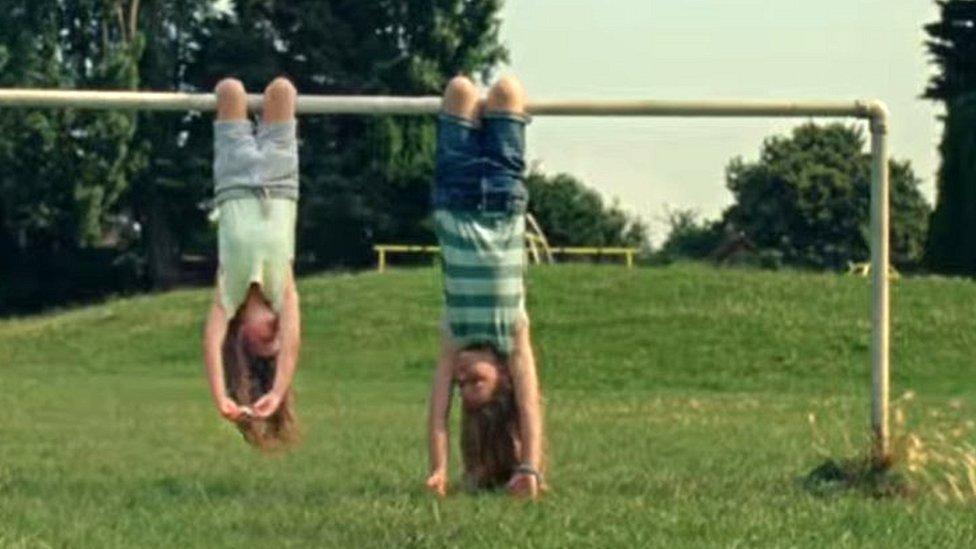 Undated screen grab from Advertising Standards Agency of Dairylea TV advert which shows two girls hanging upside down from a football goal before one opened the cheese triangle snack and ate it, has been banned following complaints that it could encourage unsafe behaviour.