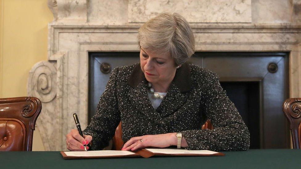 Theresa May writing at letter in downing street