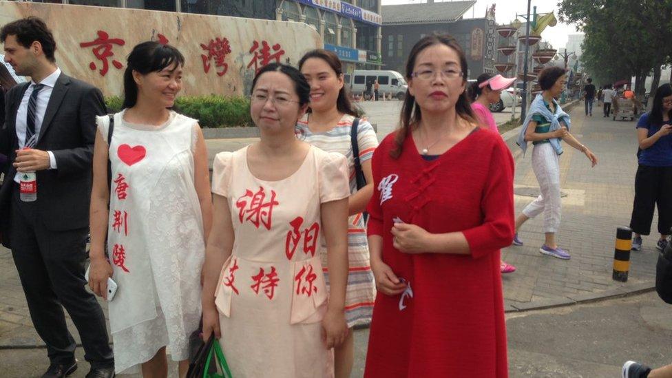 Wives protesting outside the top prosecutor with husbands' names stuck on dresses