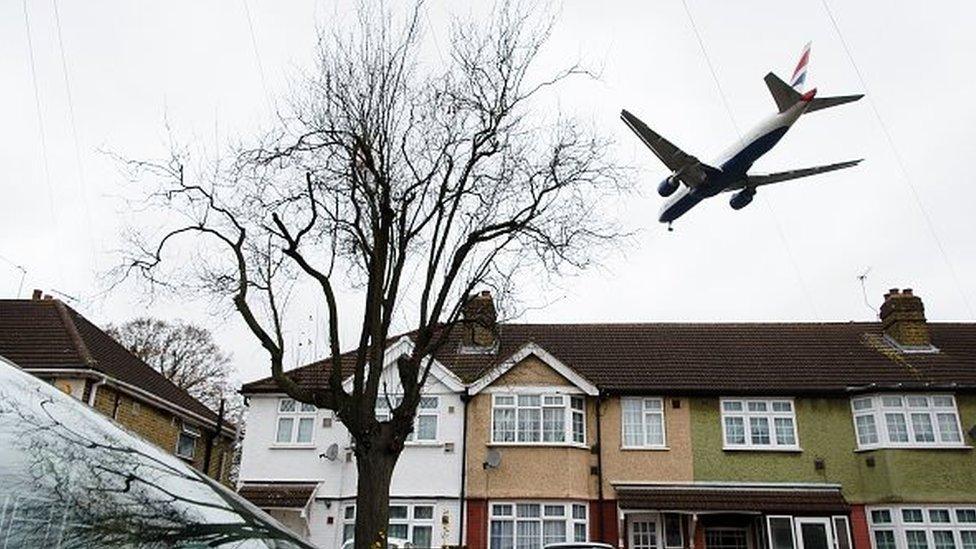 An aircraft flies over residential houses in Hounslow