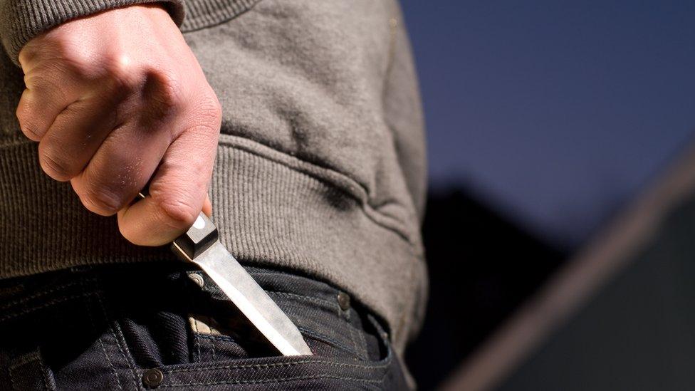 Man putting / hiding a knife into the pocket of his trousers