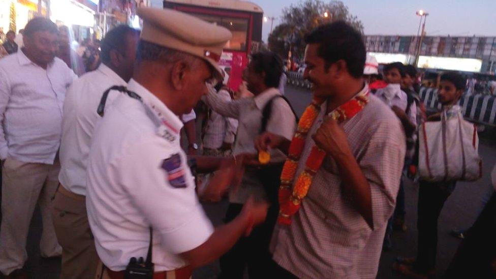 A police officer giving a man a flower garland to wear