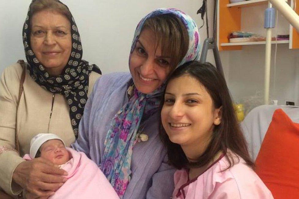 Fariba Kamalabadi (centre) holds her newborn grandchild