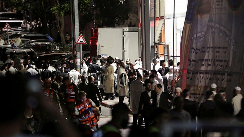 Jewish worshippers and rescue workers stand outside a synagogue where a grandstand collapsed during a religious celebration in Givat Zeev, in the occupied West Bank, May 16, 2021