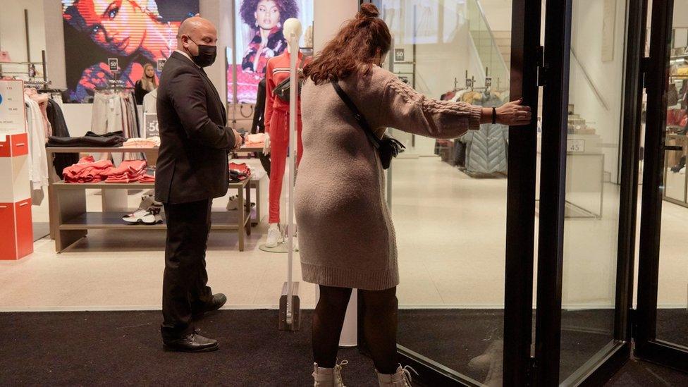 A saleswoman closes the door of a shop in a shopping street on December 18, 2021 in Rotterdam, Netherlands.