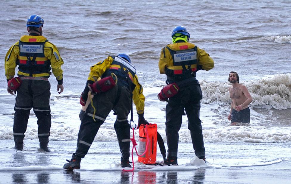 A coastguard search and rescue team ask a swimmer to come out of the sea in New Brighton, Merseyside, on 18 Fenruary 2022