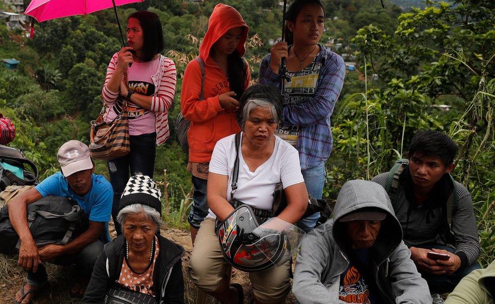 Relatives of those caught in the landslide wait as rescuers dig for bodies