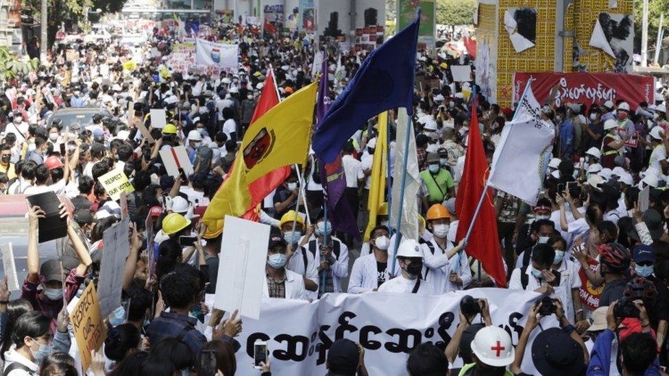 Demonstrators hold flags during a protest against the military coup, in Yangon, Myanmar