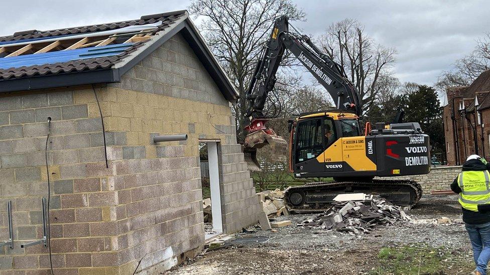 A digger is demolishing the Captain Tom spa building