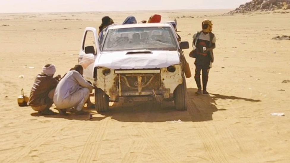 People in and around an open-top truck in the desert