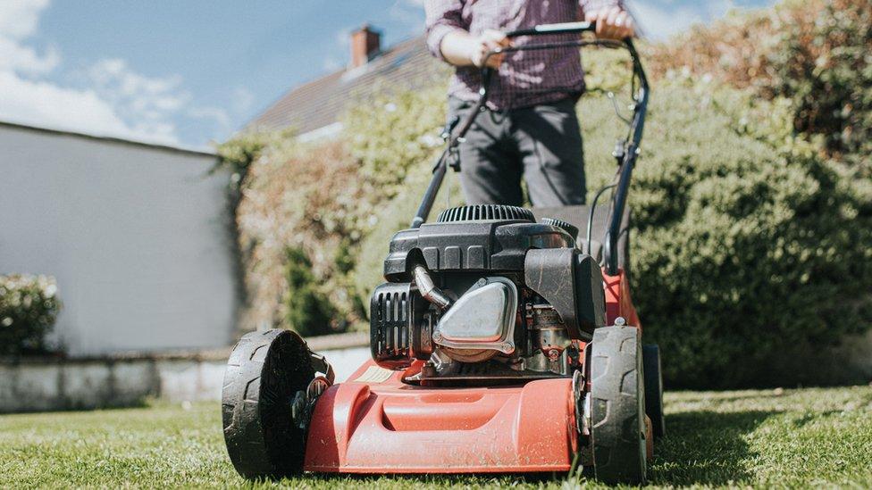 A man pushes a lawnmower