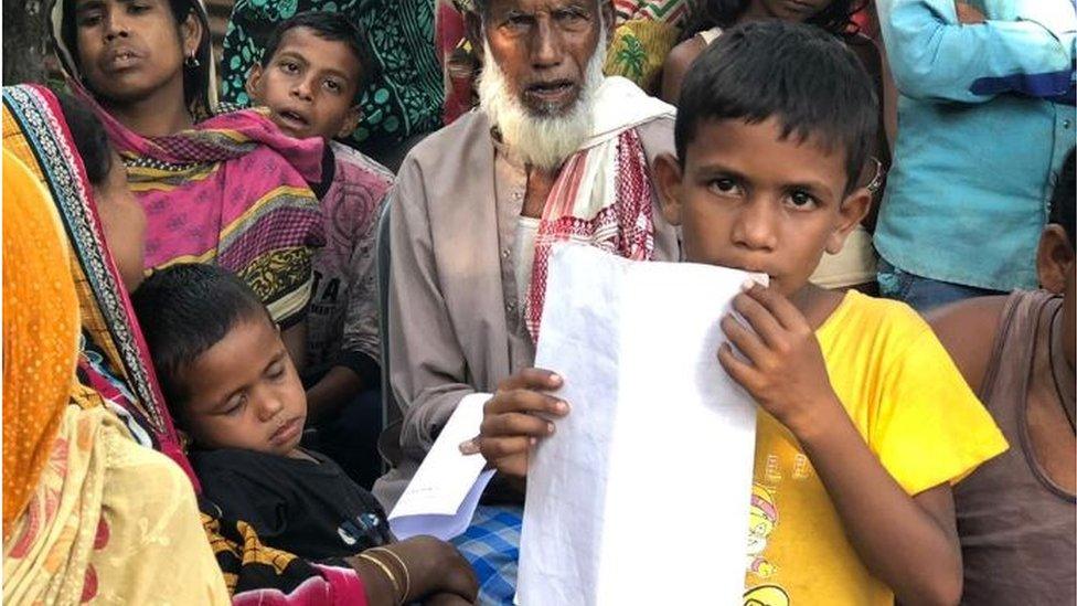 A boy holding up his documentation papers in Assam