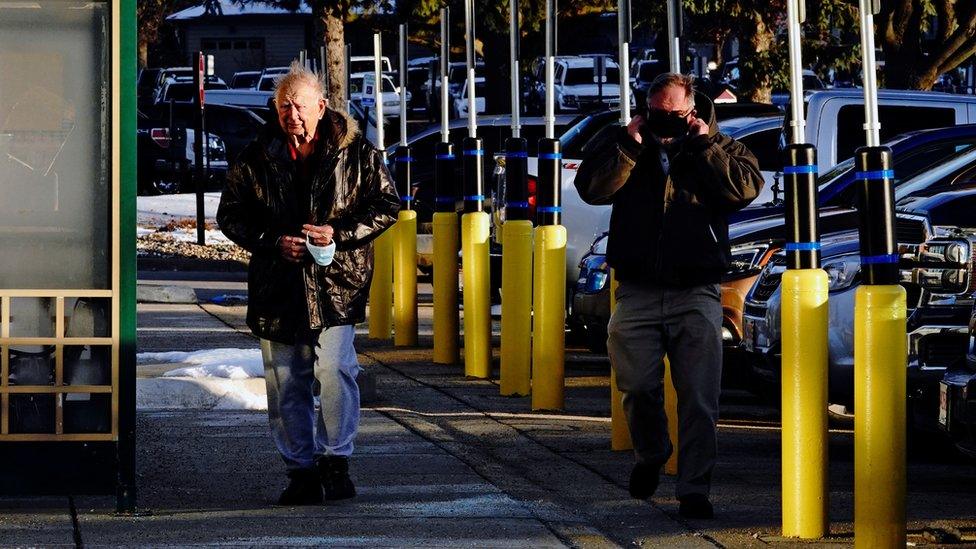 Two men putting on a face mask as they walk in Sioux Falls, South Dakota