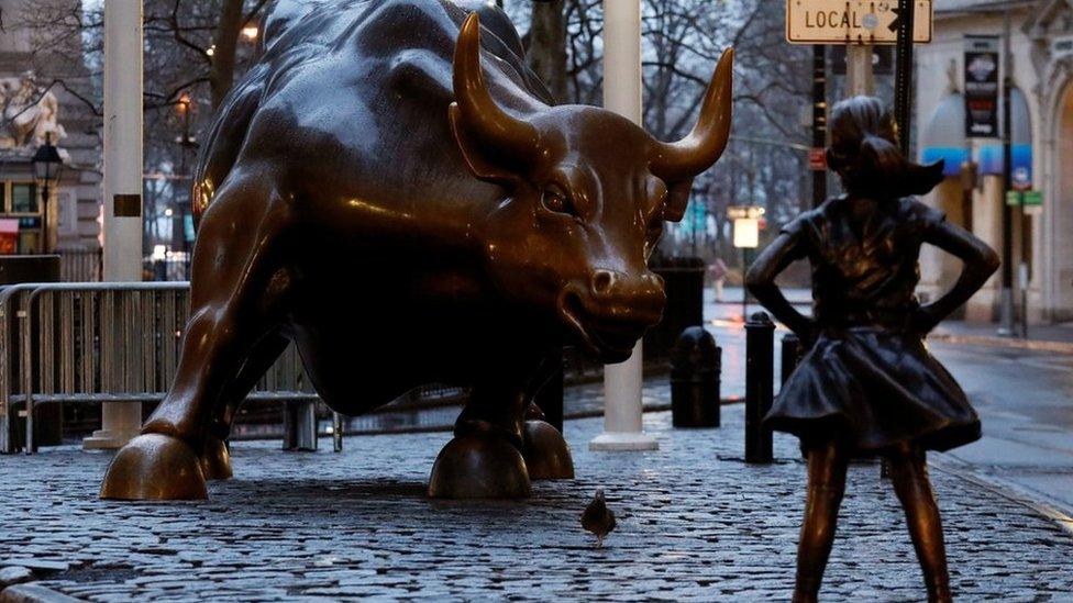 A statue of a girl facing the Wall St. Bull is seen, as part of a campaign by a US fund manager State Street to push companies to put women on their boards, in the financial district in New York