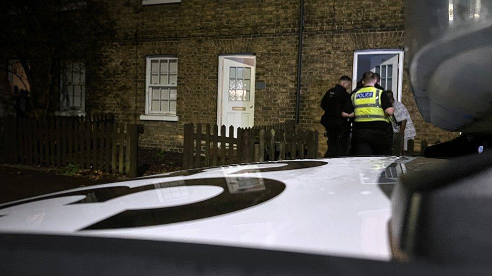 Officers outside a house with police in the foreground