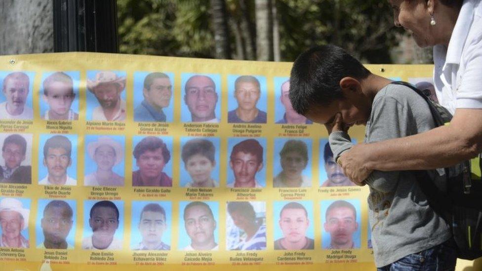 A child cries in front of a banner with the portraits of disappeared people on 25 September, 2015 in Medellin, Antioquia department, Colombia.