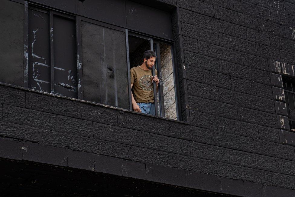 Mohamed Abu Aliya looks from the window of his burned house, which he said could now be structurally unsound.