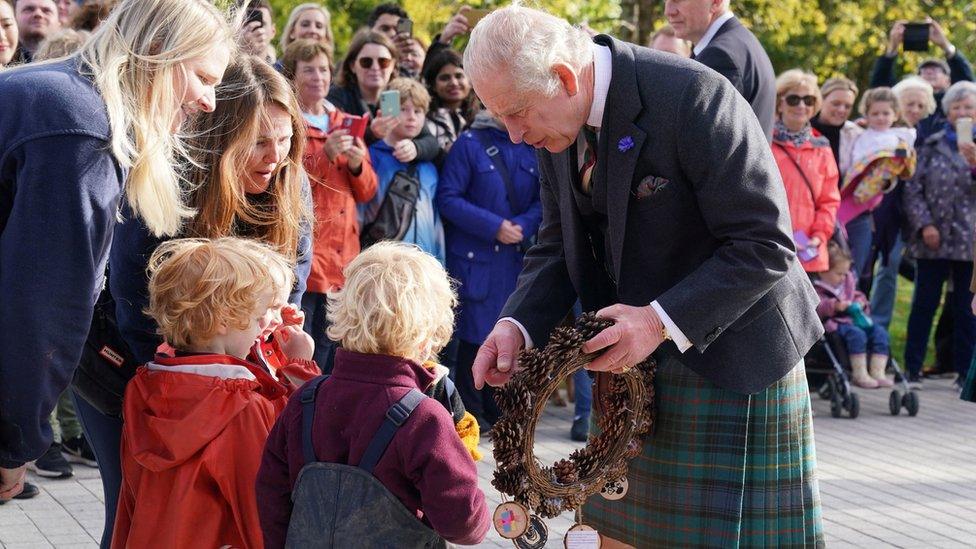 Children from an outdoor nursery handed the King a wreath made of pine cones