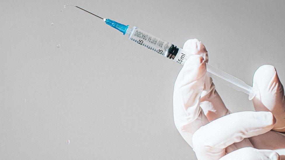 syringe in gloved hand