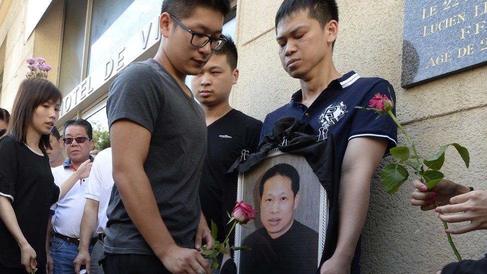 Family members and relatives hold a portrait of Chinese Zhang Chaolin as people light candles and lay flowers during a tribute ceremony, outside the city hall in Aubervilliers, north-eastern suburbs of Paris, on August 14, 2016.