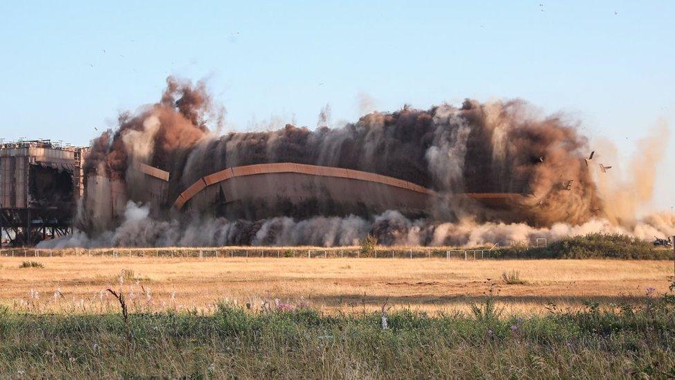 The building in mid collapse with plumes of smoke and dust rising