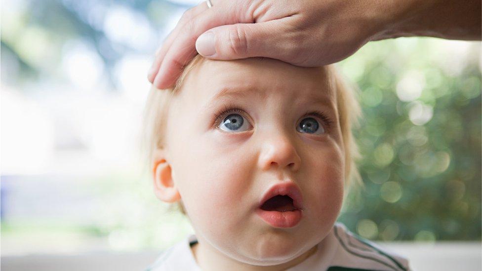 Baby with a hand on his head