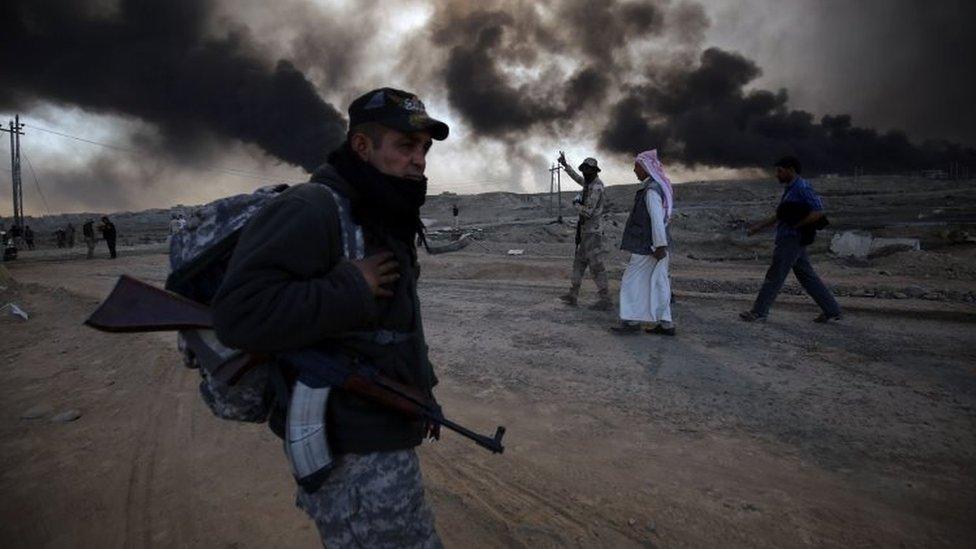 A Sunni fighter from the Popular Mobilisation Forces stands guard in an area east of Mosul, as displaced Iraqi families flea areas of unrest (22 October 2016)