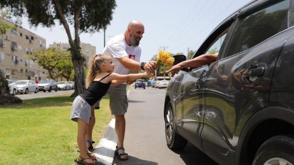 Israelis hand out flowers in Ashkelon on the first day of the ceasefire