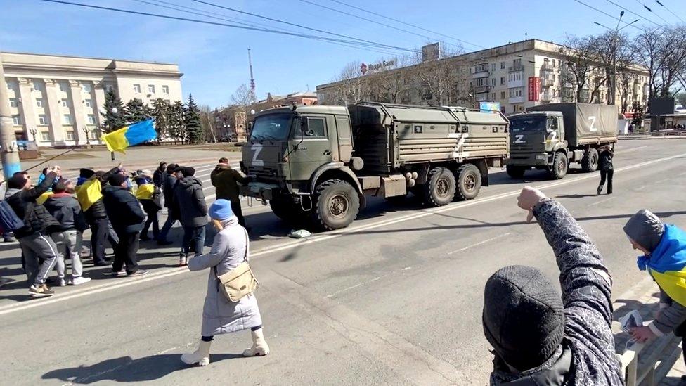 Demonstrators with Ukrainian flags chant "go home" to Russian military vehicles at a pro-Ukraine rally in Kherson, 20 March 2022