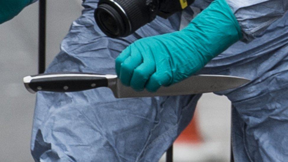 A police worker recovering a knife at the scene