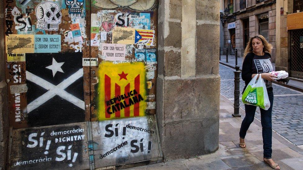 A woman walks past pieces of Catalan pro-independence graffiti on some doors in Barcelona